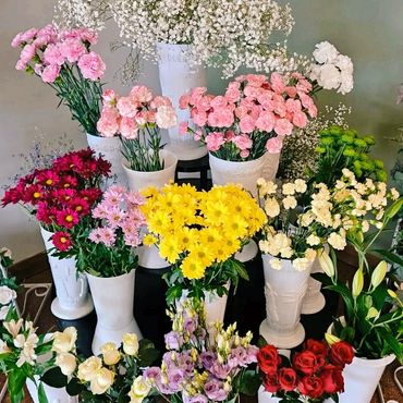 A colorful arrangement of various flowers in white vases.