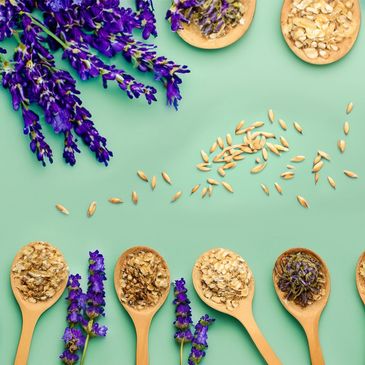 Lavender flowers and oat seeds on a green surface. Some wood spoons with oats and lavender flowers.