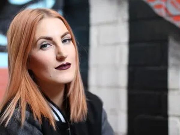 Young woman with red hair and dark lipstick posing confidently.