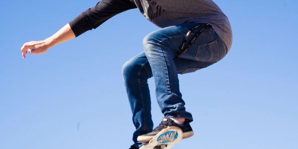 Person jumping mid-air wearing jeans and sneakers.
