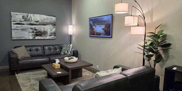 Modern living room with black leather sofas and ambient lighting.