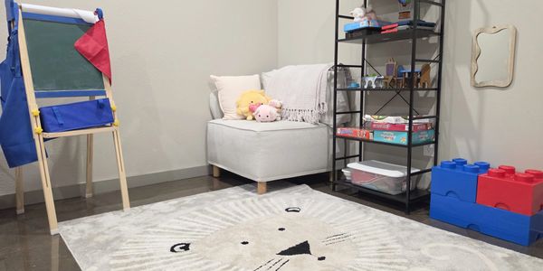 Cozy children's playroom with toys, a chair, and a lion rug.