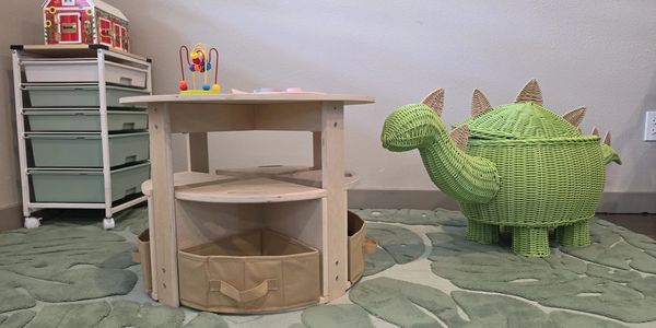 Children's play area with a toy table and a green dinosaur storage basket.