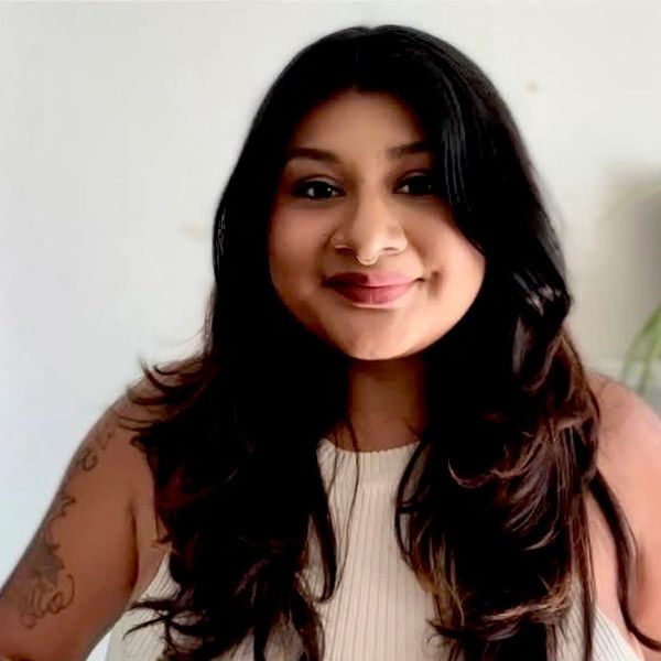 Smiling woman with long black hair and a nose ring.
