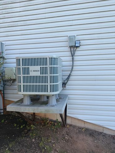 Bosch air conditioning unit mounted on a platform outside a house.
