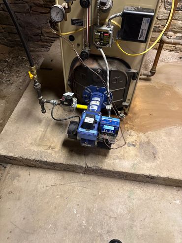 A furnace with a blue Carlin burner installed on a concrete platform.