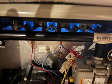 Inside view of a gas furnace showing blue flames and wiring.
