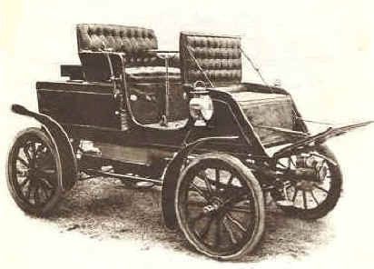 Early vintage car with large spoked wheels and leather seats.