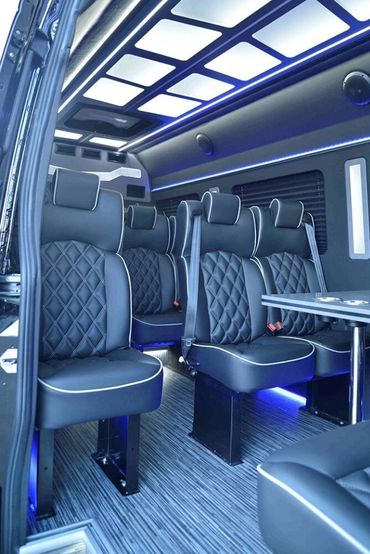 Luxurious van interior with black leather seats and ambient blue lighting.