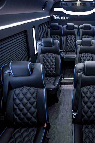 Luxury black leather seats inside a modern van with ambient lighting.