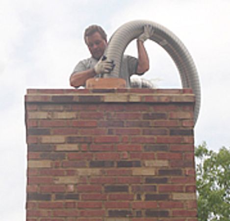 Man cleaning a chimney using a vacuum hose.