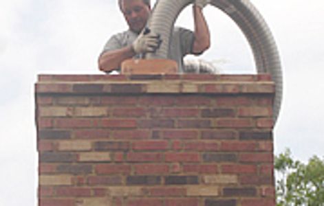 Man cleaning a chimney using a vacuum hose.