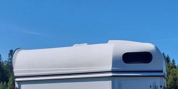 White trailer with a curved roof against a clear blue sky.