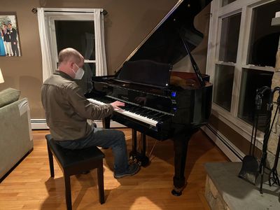 Mark Bushell servicing a grand piano inside a home