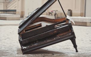 Grand piano in disrepair with leg missing
