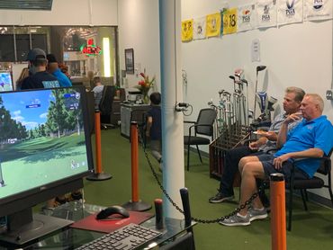 two people looking at the golf game on the monitor