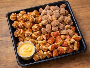 Tray of assorted bite-sized pretzel snacks with a cheese dip.