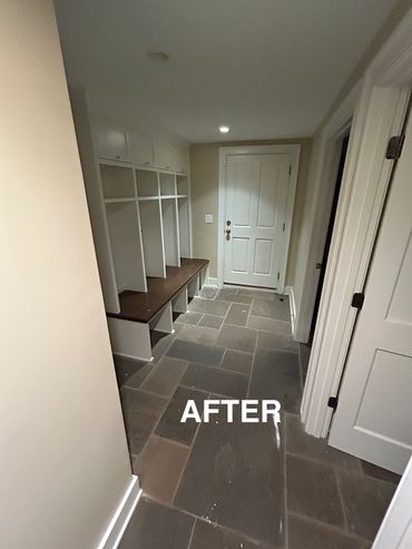 Clean and organized entryway with built-in cubbies and stone tile flooring.