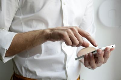 Person using a smartphone with one hand and touching the screen with the other.