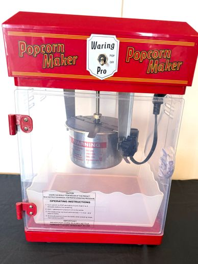 Vintage red Waring Pro popcorn maker with clear door and metal kettle.