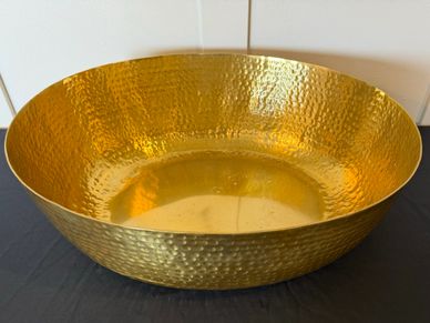 Large hammered gold metal bowl with shiny finish.
