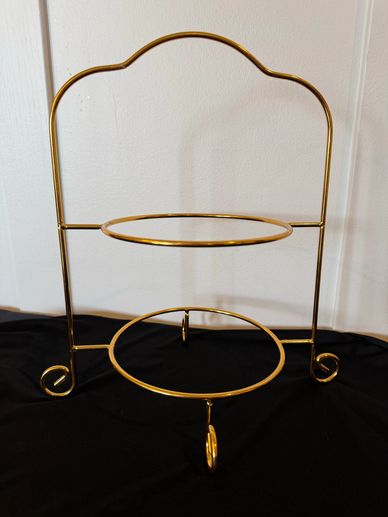 Gold metal two-tier stand on black fabric background.