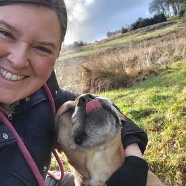 Lu cuddling a dog with its tongue out