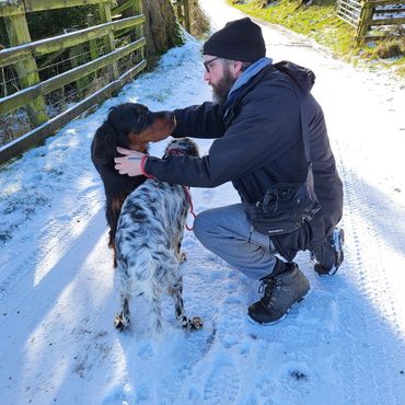 Adam kneeling in the snow with an English Setter and a Gordon Setter