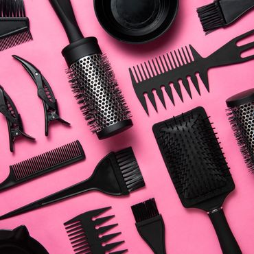 Black hair styling tools arranged on a pink background.