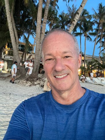 Man smiling on a tropical beach with palm trees.