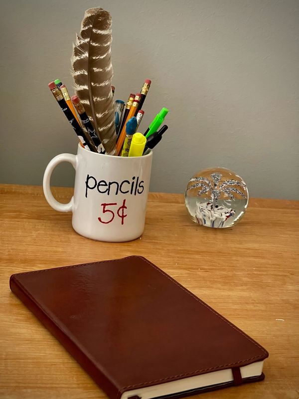 a notebook and a mug with pencils 