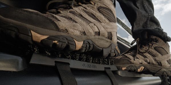 Boots stepping on a brush on a vehicle step