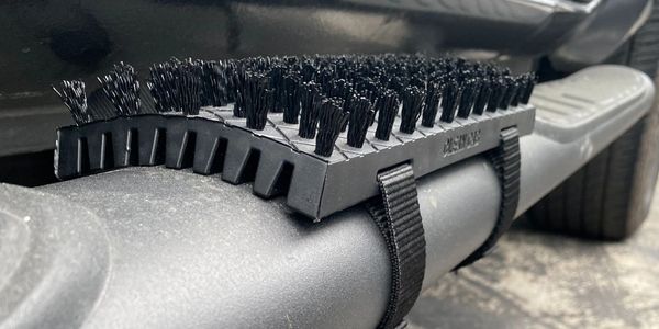 A boot brush strapped to the vehicle step