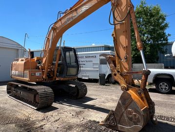 A rusty orange excavator parked outdoors.