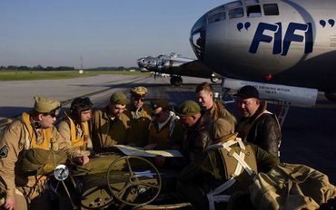 Men dressed up in WWII uniform with "FIFI" airport in the back.