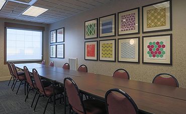 A large meeting table with colorful framed pictures on a tan wall.