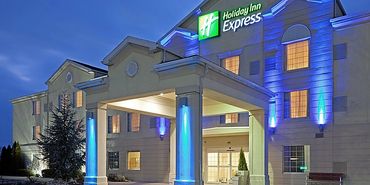 Outside of the Reading Holiday Inn Express at night. A large white building with blue lights.