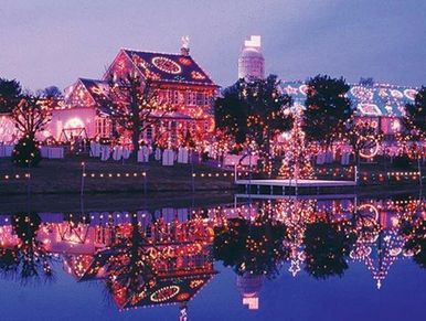 A small village covered in string lights reflecting in a body water.