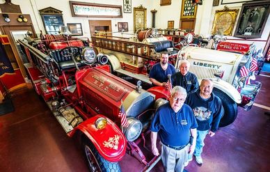 Four men standing in front of old fire cars.
