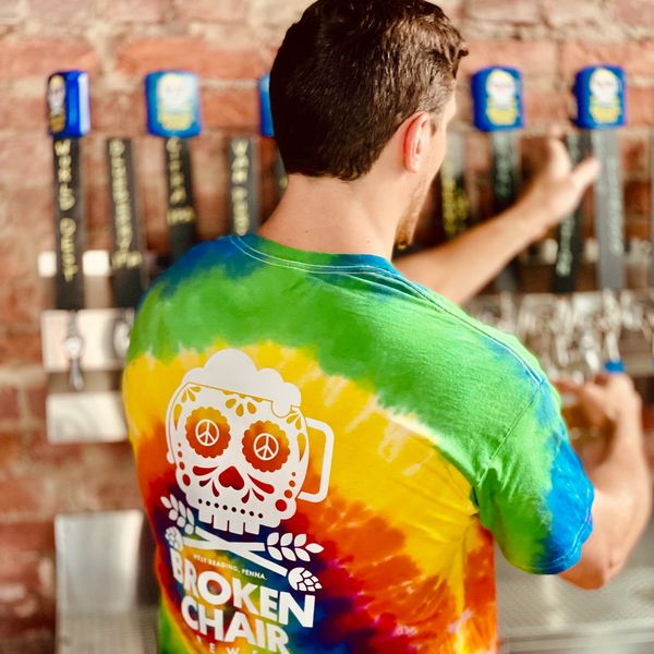 Man in tie dye shirt pours draft beer.
