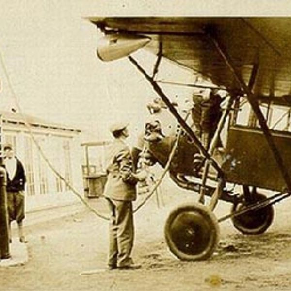 Old black and white picture of man filling up his small aircraft with gas.