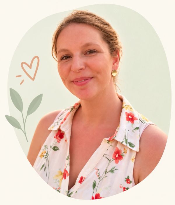 Vrolijke vrouw met bloemenjurk en gouden oorbellen.
