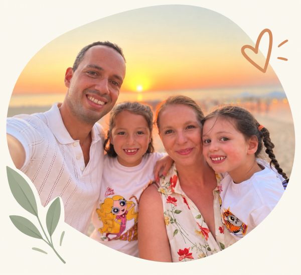 Familie neemt selfie bij zonsondergang op het strand.