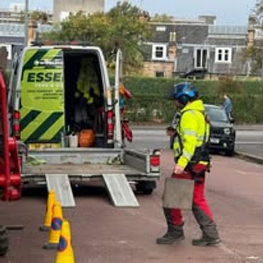 Worker walking near utility van with open back.