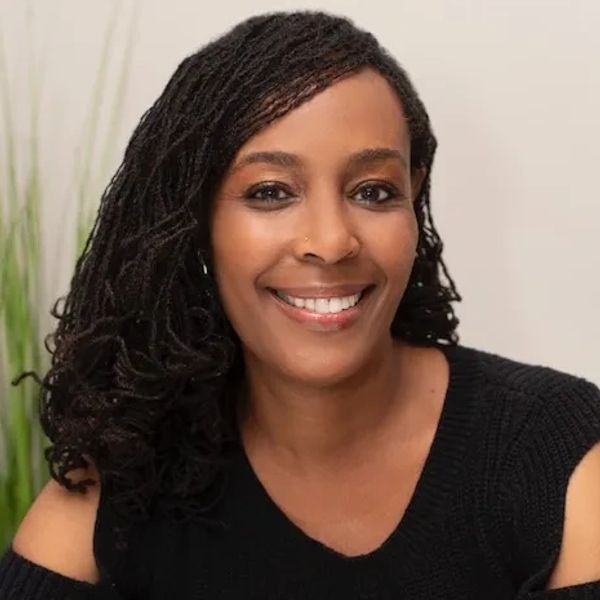 Smiling woman with braided hair wearing a black top.
