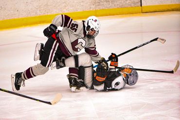 Two youth ice hockey players collide on the rink during a game.