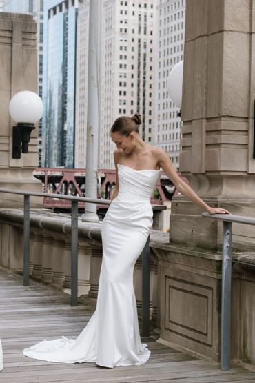 A classic fitted satin wedding dress with rushing details, and a cat eye neck line