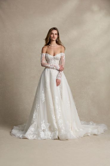 A dramatic lace A-line wedding gown with sleeves and exposed boning