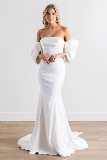 A fitted wedding gown with a straight neckline featuring princess off the shoulder straps