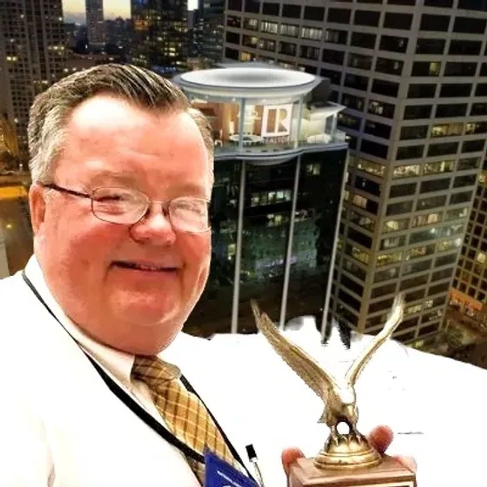 Man in glasses holding an eagle trophy with city buildings in the background.